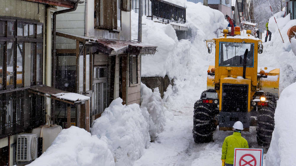 A snow plow clearing the road of deep snow in Myoko Kogen Japan